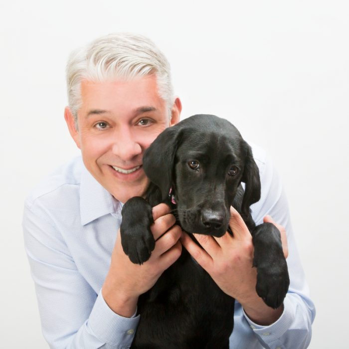 Man holding a black lab puppy