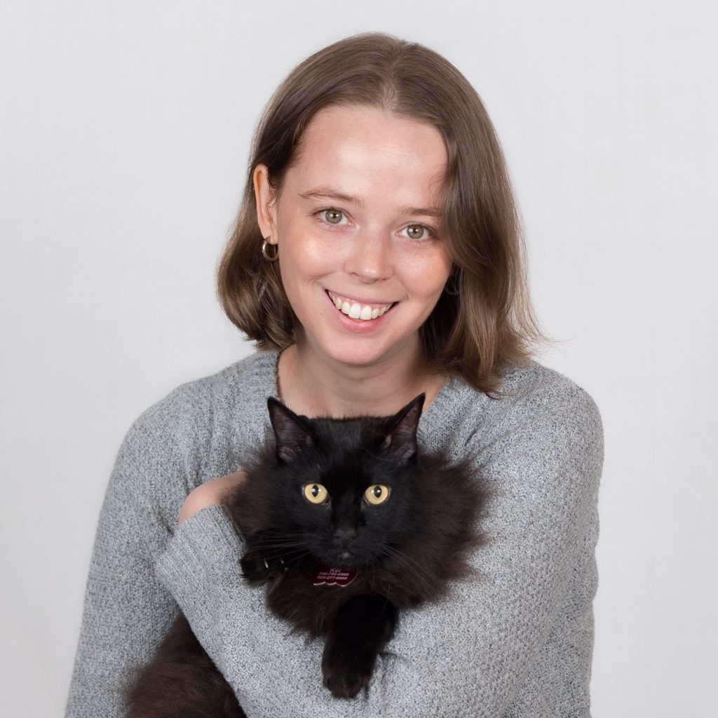 Annie smiling and holding a cat