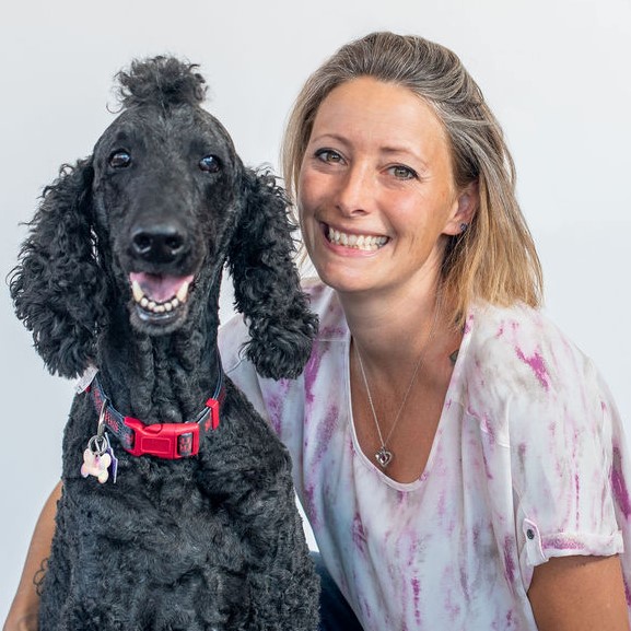 Adria Fusco smiling with a black poodle